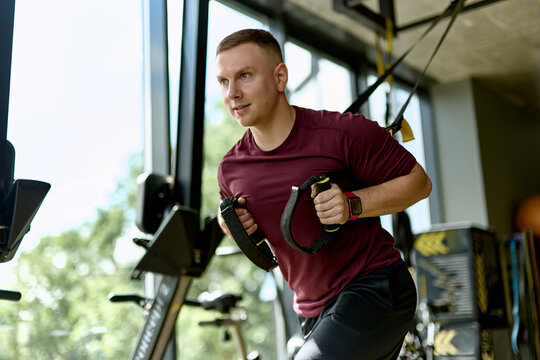 Man Training with Suspension Straps in Modern Gym