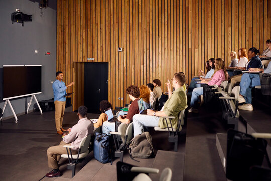 Young man is speaking to the students in the lecture room.