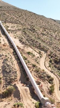 Aerial shot of the Los Angeles Aqueduct as it passes over some low mountains in California. The aqueduct supplies water to Los Angeles and Southern California. Vertical video.