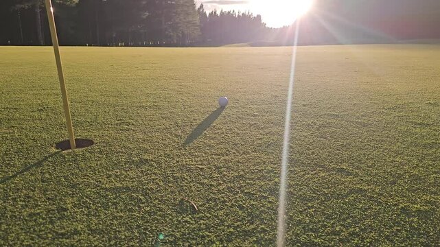 Golf ball rolls toward the hole on a sunny afternoon at a golf course