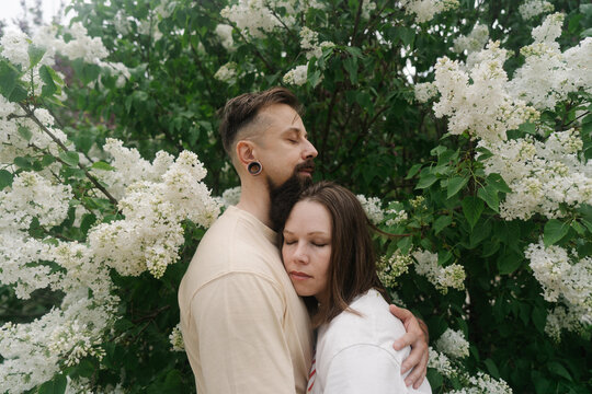 Couple embracing beside blooming lilac bush
