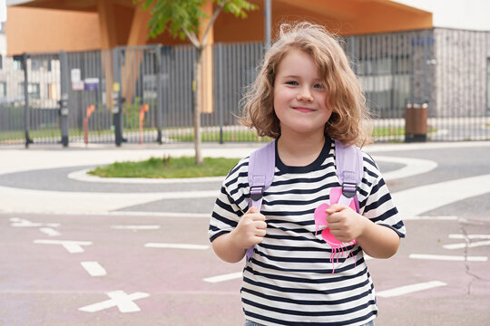 Girl with backpack stands on walkway near playground