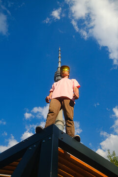 Man Stands on Structure With Urban Tower in City Background