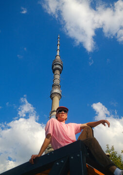 Man Sits on Roof With Tower in Background Under Blue Sky