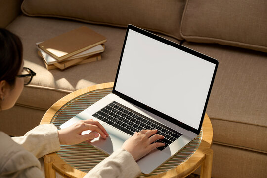 Woman working on laptop with blank screen at home, cozy workspace