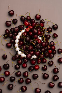 Pearl necklace under pile of red cherries