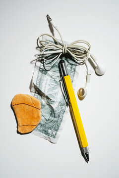 Piece of rock on a one dollar bill with cabled earphones and pencil