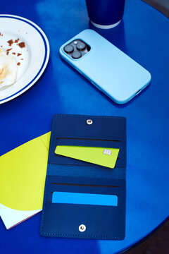 Wallet, phone, and coffee cup on blue table
