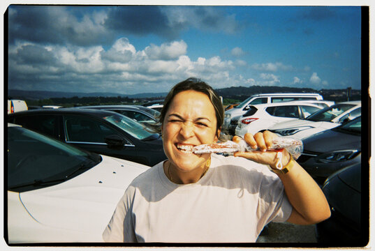 Woman enjoying snack sausage in parking lot outdoors