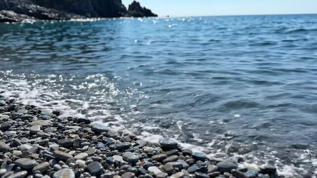 Pebble beach with gentle waves lapping the shore under a clear blue sky