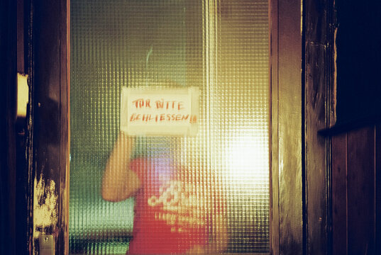 Handwritten German sign on textured glass door