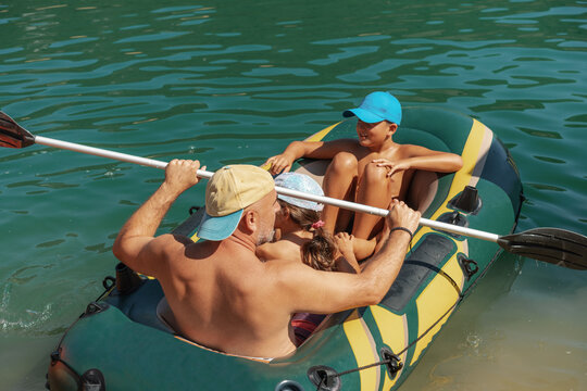 Father And Children Enjoying a Ride in Paddle Inflatable Boat