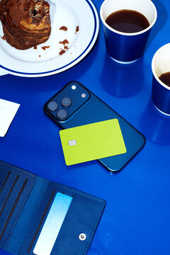 Credit card on a phone on a blue table in a caf&eacute;.