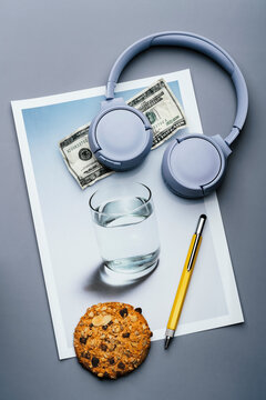 Headphones, pencil, and dollar bill and cookie on glass of water photo
