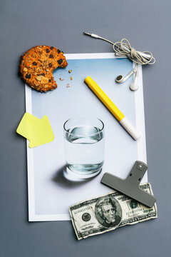 Cookie, variety of stationery and dollar bill on glass of water photo