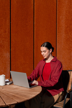 Woman focused on remote work with laptop at cafe on a terrace