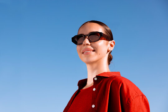 Portrait of smiling woman embracing bold style in sunglasses