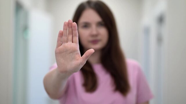 Woman showing stop gesture with open hand, expressing refusal, boundary, safety, and protection.