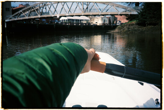 Person Rowing a Boat Near a Bridge on a River in Springtime