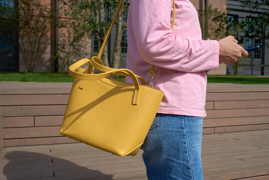 Anonymous woman with yellow bag holding mobile phone