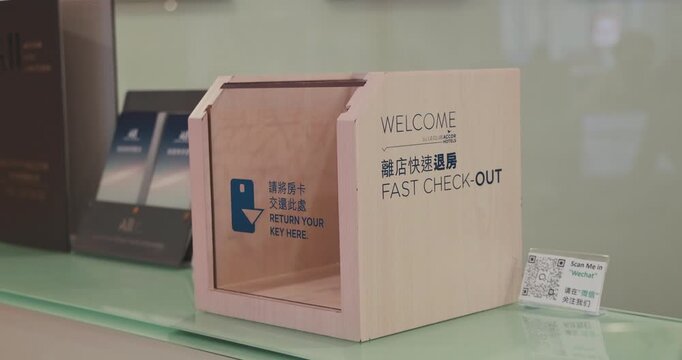 Hong Kong, 18 June 2026 - Hong Kong, 18 June 2026. Wooden express check-out key return box at Ibis Hotel front desk counter, modern contactless hospitality service, editorial documentary.