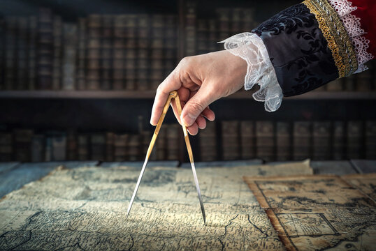 The captain of the old ship paves the course with the help of vintage maps and nautical divider. Old discovery, explorer, history, pirates, travel, geography and navigate background.