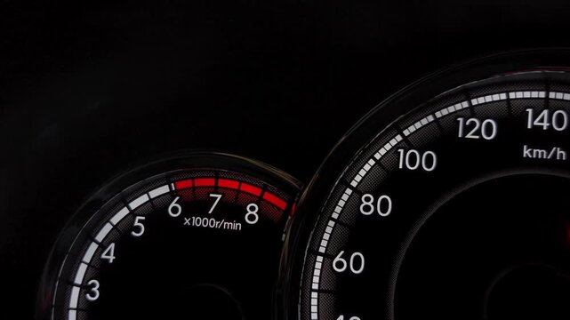 Close-up of green left turn signal arrow indicator light illuminated on car dashboard speedometer