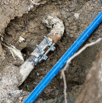 Old Leaking Drinking Water Pipe with Repair Clamp Beside New Water Line