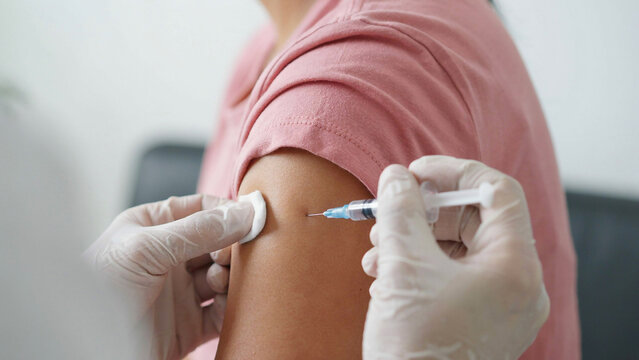 Vaccination shot being administered to a woman in a clinical setting with copy space