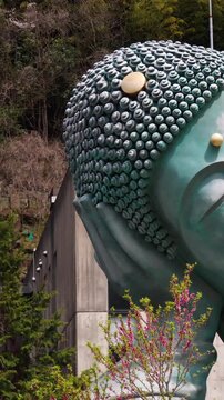 Reclining Buddha giant bronze statue at Nanzoin Temple in Sasaguri, Japan, Kasuya district, Fukuoka Prefecture, Kyushu Island, with cherry blossoms and bamboo forest on spring day, peaceful landscape