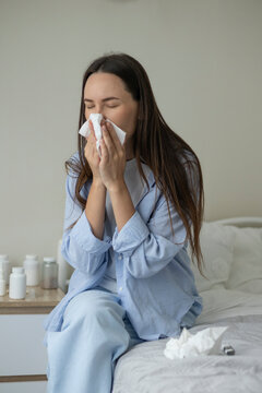 Sick woman resting in bed with symptoms of fever, runny nose and cough during an illness