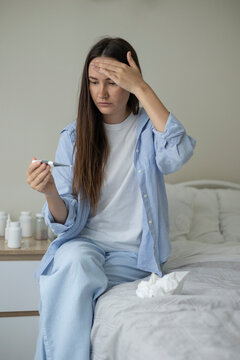 Sick woman resting in bed with symptoms of fever, runny nose and cough during an illness
