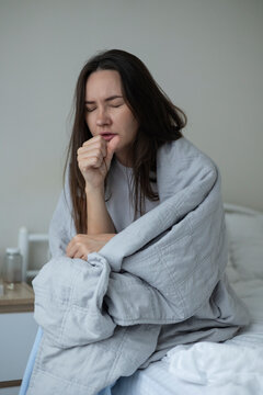 Sick woman resting in bed with symptoms of fever, runny nose and cough during an illness
