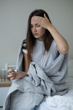 Sick woman resting in bed with symptoms of fever, runny nose and cough during an illness