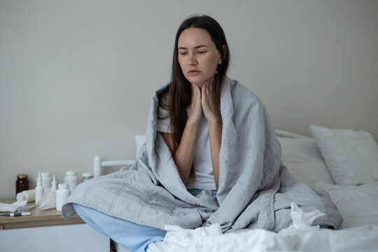 Sick woman resting in bed with symptoms of fever, runny nose and cough during an illness