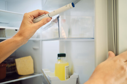Female hand taking a GLP-1 injection pen from refrigerator, weekly weight loss home therapy
