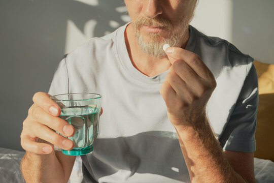 Man taking oral medication with glass of water for health and wellness
