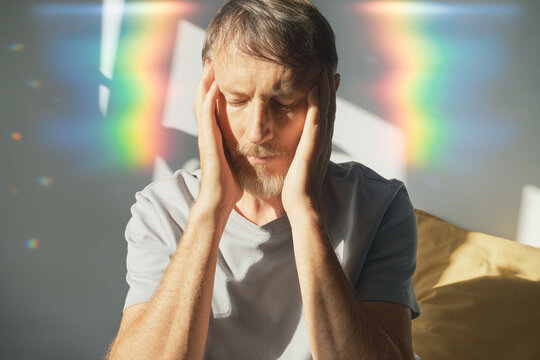Man experiencing painful migraine with visual disturbance and light sensitivity