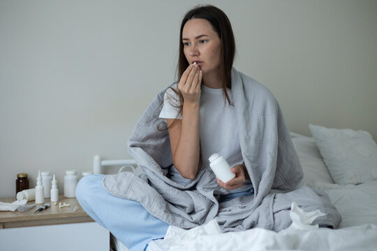 Sick woman resting in bed with symptoms of fever, runny nose and cough during an illness