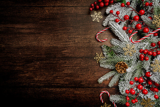 Christmas and New Year background with a festive scene with gold and red Christmas ornaments and fir tree branches on a wooden background, symbolizing holiday spirit and elegance.
