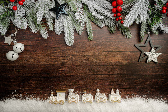Christmas toy train travels through a miniature white snowy forest. Minimalist Festive Christmas scene, dark wooden background with copy space.