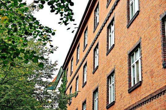 Orange brick building with windows and green trees