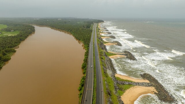 Aerial view of Maravanthe beach with a highway separating the Souparnika river and the Arabian Sea in Maravanthe, Karnataka, India.