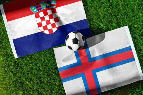 Croatia vs. Faroe Islands football match. National flags on green grass with soccer ball in the middle. Football background for international match.