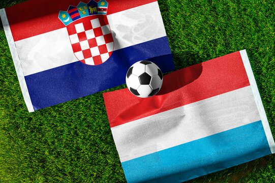 Croatia vs. Luxembourg football match. National flags on green grass with soccer ball in the middle. Football background for international match.