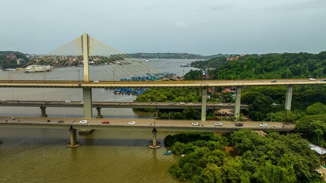 Aerial view of the Atal Setu cable-stayed bridge spanning the Mandovi River with traffic and surrounding lush greenery in Panaji, Goa, India.