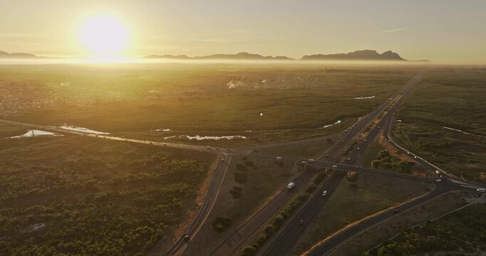 Cape Town South Africa Aerial v100 flyover Macassar capturing a highway interchange cuts through the vast, sun-drenched landscape of Khayelitsha township - Shot with 5k Camera - Jan 11th 2024