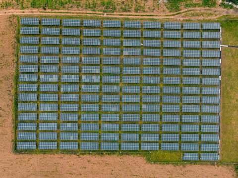 Aerial view of a large solar farm with rows of photovoltaic panels arranged in a grid pattern, surrounded by rural landscape in Ogun State, Nigeria.