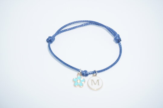 Blue cord charm bracelet with blue flower pendant and initial M isolated on white background
