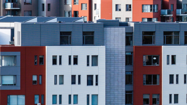 Aerial view of a modern apartment complex with a distinctive red and white facade and grey paneling in Delft, Netherlands.